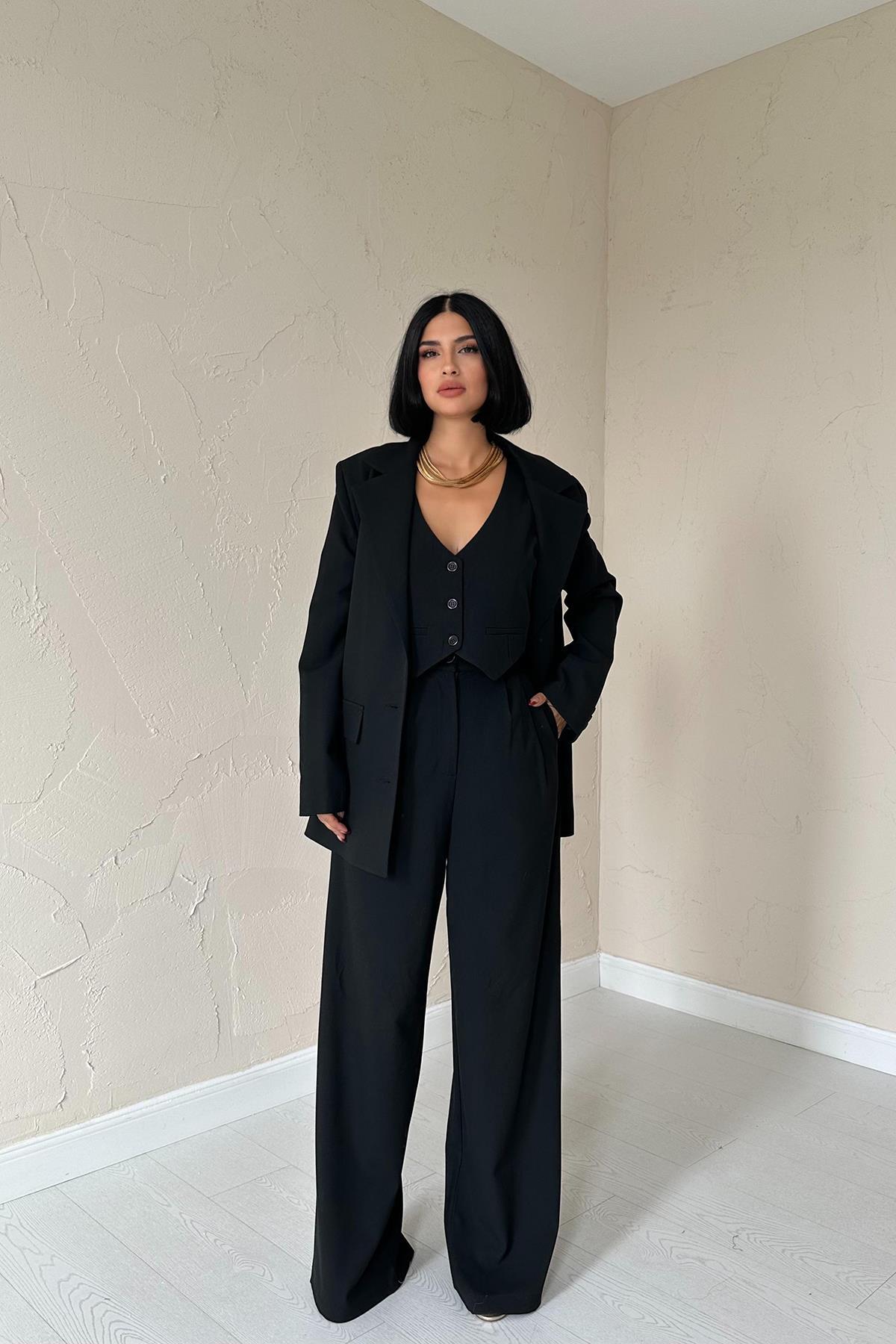 Woman wearing tailored black trio set with blazer, vest, and wide-leg trousers.