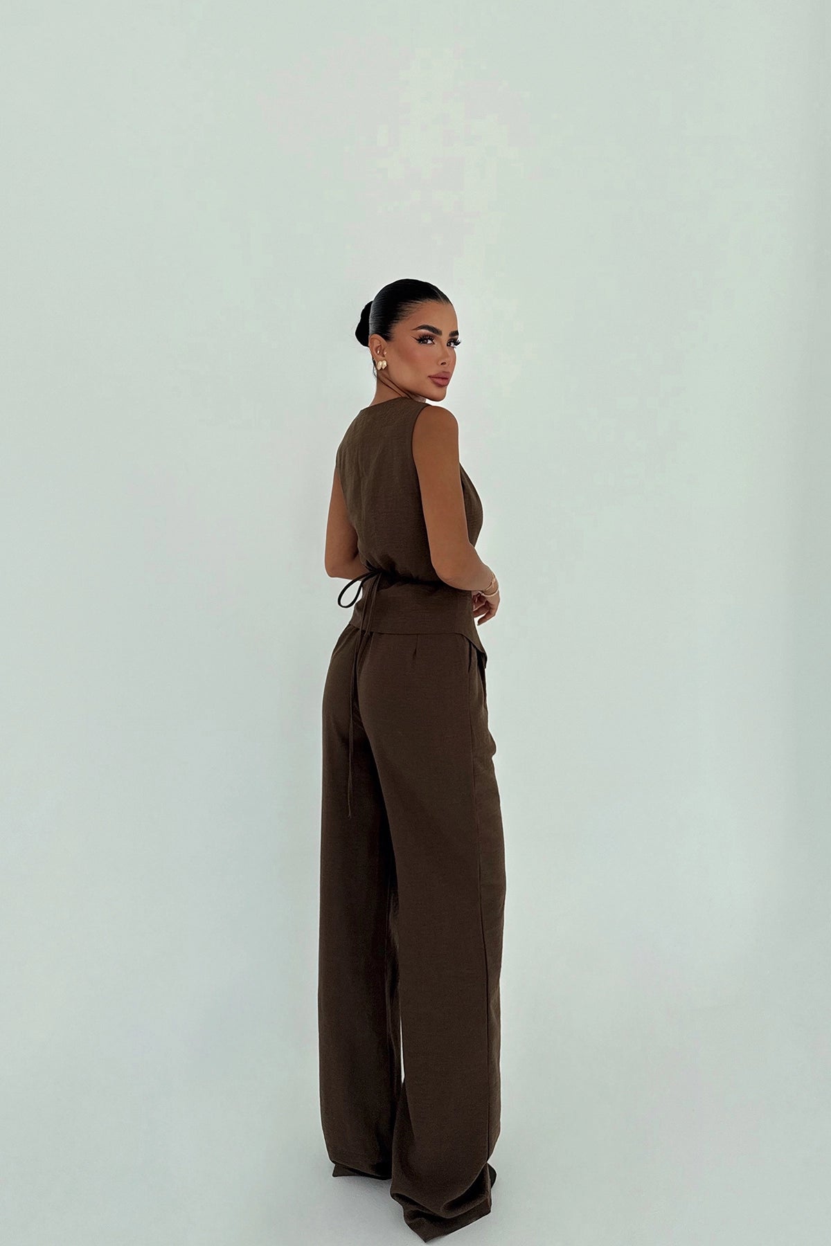 Back view of mocha brown sleeveless suit set with tie detail.