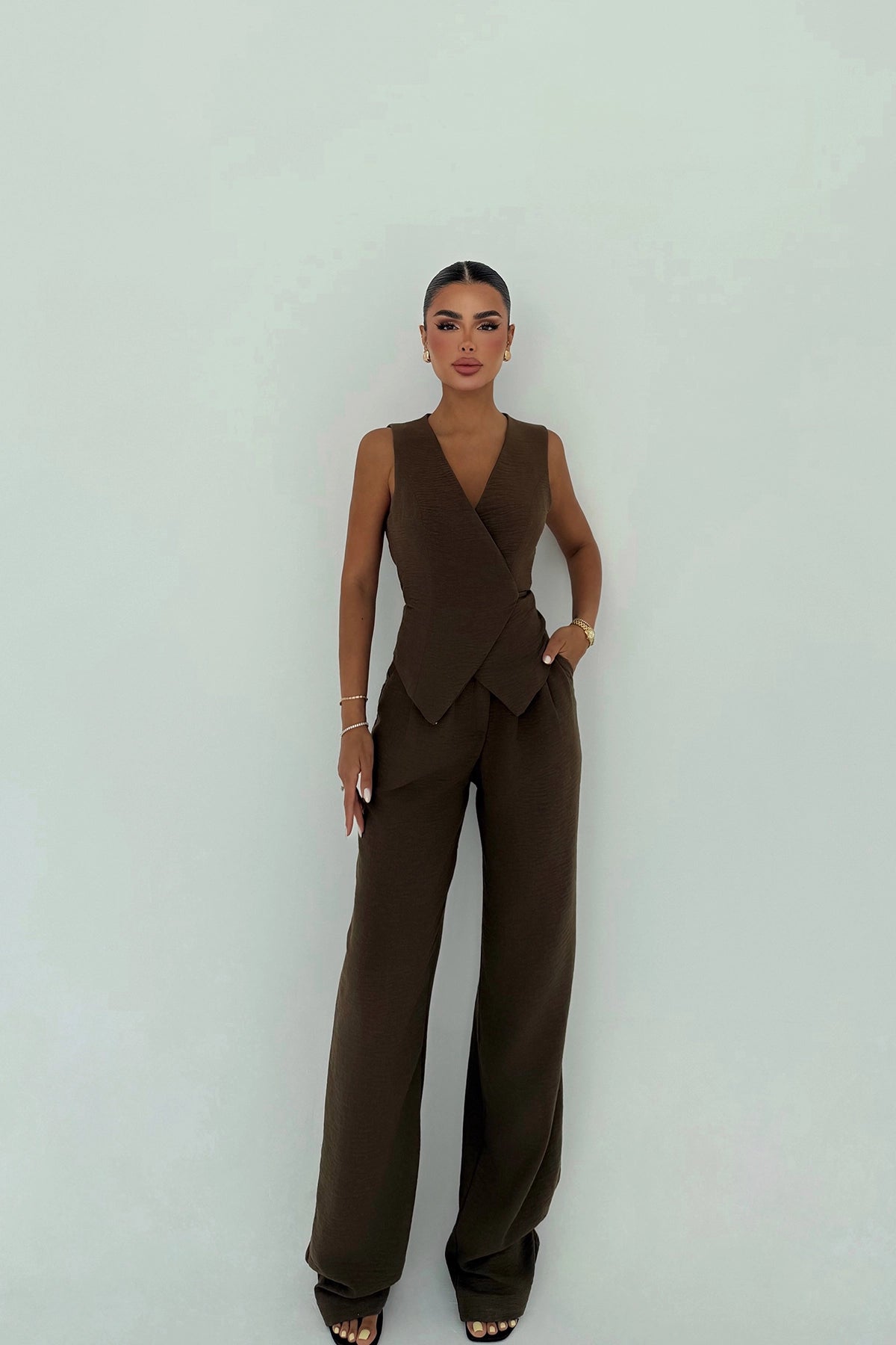 Woman wearing mocha brown sleeveless wrap vest with matching wide-leg trousers.