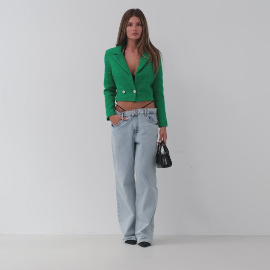 Model walking towards the camera wearing emerald green cropped bouclé blazer – chic women’s tailored jacket from LARYVOE.
