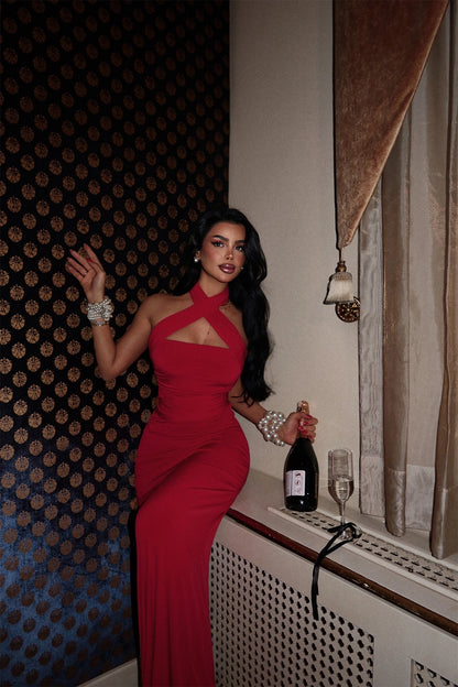 Scarlet multi-tie gown with asymmetric neckline, photographed indoors in an elegant room.